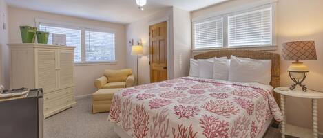 A bedroom with a bed, a wardrobe, a chair, a desk, and a ceiling fan.