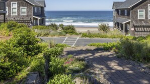 Uma área residencial costeira com duas casas, um caminho de entrada pavimentado e vista para o mar.
