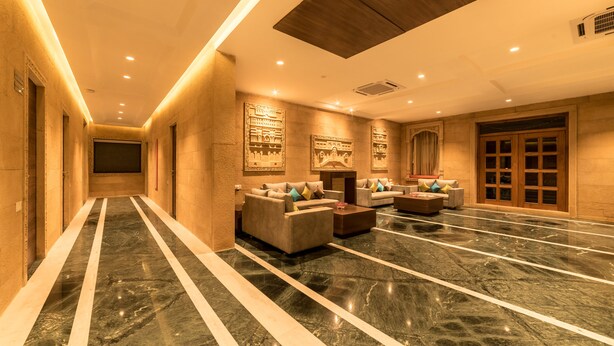Un vestíbulo de hotel con piso de mármol, sofás y una gran puerta de madera.