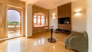 Un salón espacioso con una mesa de centro de cristal, un sofá, un televisor de pantalla plana montado en la pared y un balcón con vistas.