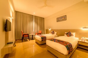 A hotel room with two beds, a TV, a desk, and a chair.