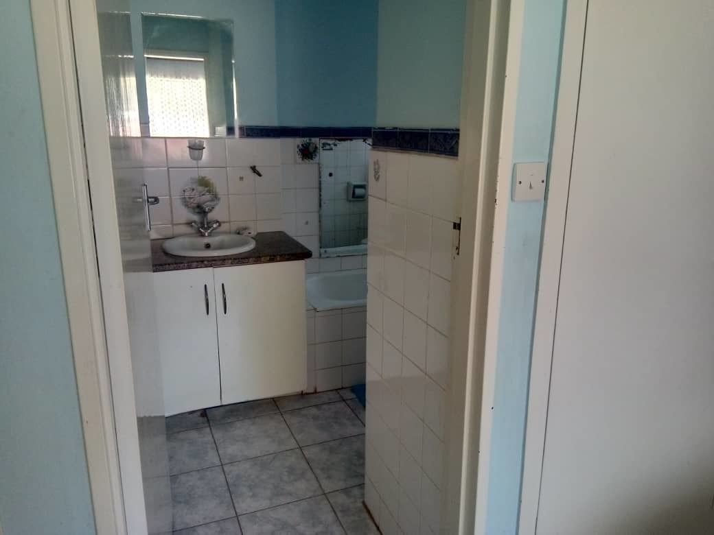 A small bathroom with a sink, mirror, and tiled floor.