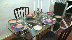 A dining table set with colorful plates, a glass top, and white candles. - Tal-Kapilluna Zebbug Guest House (Zebbug)