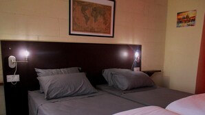 A hotel room with two single beds, a world map on the wall, and a painting of a cityscape. - Tal-Kapilluna Zebbug Guest House (Zebbug)