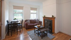 A living room with a fireplace, a dining table with chairs, a sofa, and a coffee table. - Victoria's place (Chelmsford)