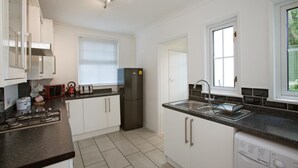 A modern kitchen with white cabinets, a black refrigerator, a gas stove, a microwave, and a dishwasher. - Victoria's place (Chelmsford)