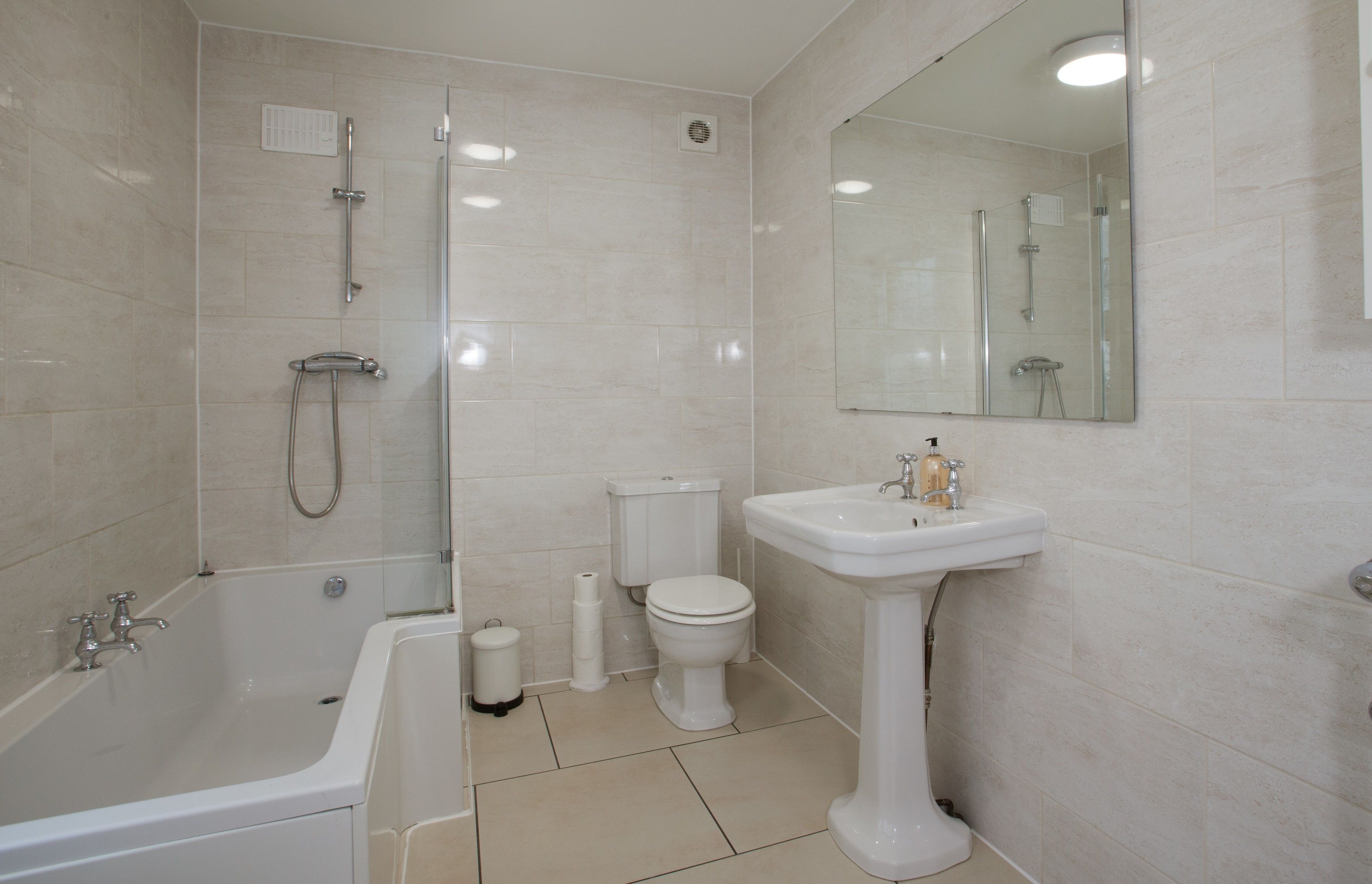 A bathroom with a bathtub, toilet, sink, and a shower area.