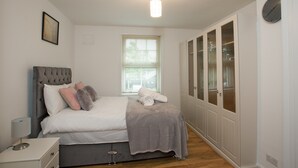 A bedroom with a bed, bedside table, and a window. - Victoria's place (Chelmsford)
