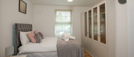 A bedroom with a bed, bedside table, and a window.