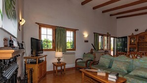 A cozy living room with a television, wooden furniture, and a window with curtains. - GC0152 Holiday cottage in La Lechuza (Vega de San Mateo)