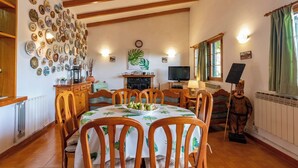 A dining area with a wooden table and chairs, a fireplace, a television, and a statue. - GC0152 Holiday cottage in La Lechuza (Vega de San Mateo)