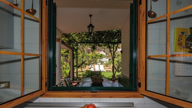 A room with a view of a garden through a wooden-framed window, a wicker basket with fruit on the counter, and a calendar on the wall. - GC0152 Holiday cottage in La Lechuza (Vega de San Mateo)