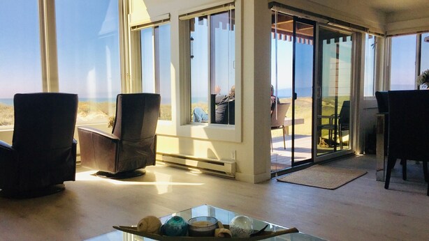Ein modernes Interieur mit einem Glastisch, einer Sitzecke und Blick auf den Strand.