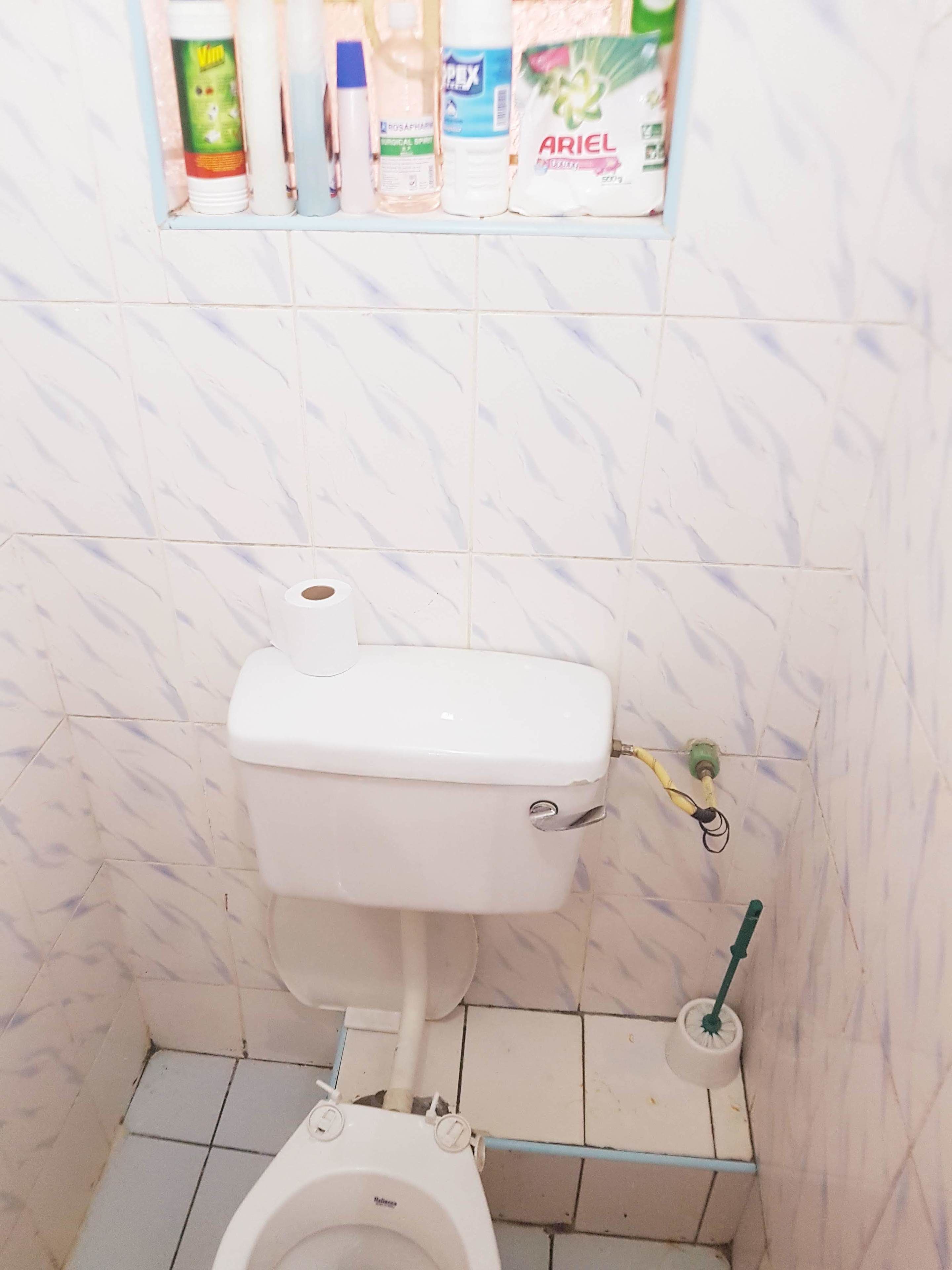 Un baño con inodoro, bidé y estante con artículos de aseo.