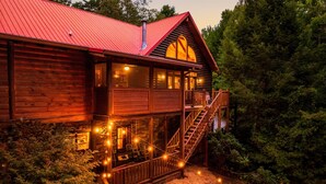 Una cabaña de madera con techo rojo, un balcón y luces colgantes.