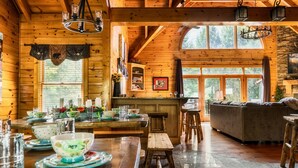 Interior de una cabaña de madera con comedor, cocina y sala de estar.