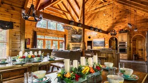 Una cabaña de madera espaciosa con comedor listo para una comida, una sala de estar acogedora y una cocina con armarios de madera.