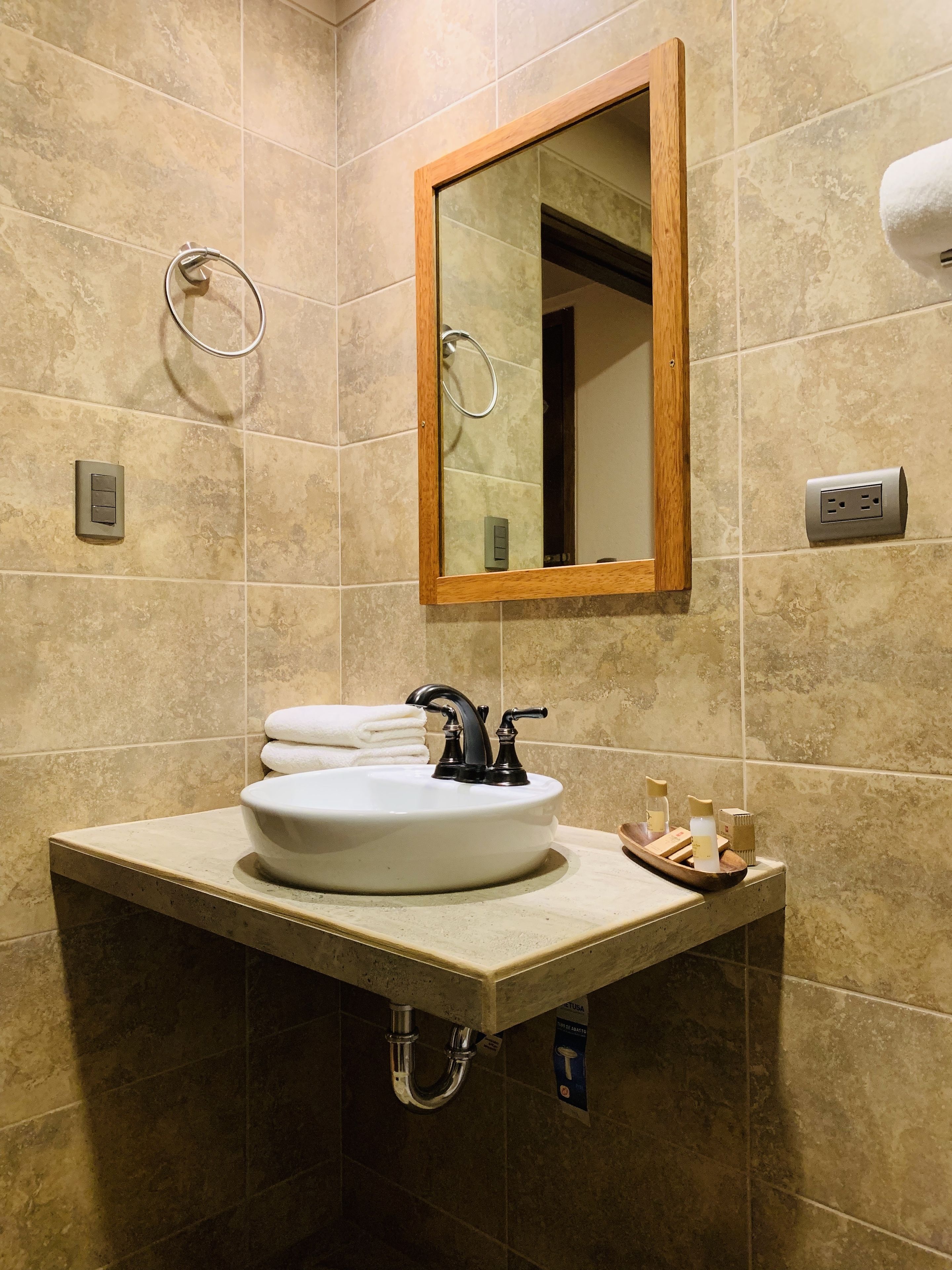 A bathroom with a white sink, a wooden-framed mirror, and a towel rack.