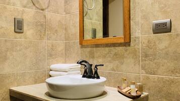 Un baño con un lavamanos blanco, un espejo con marco de madera y un perchero para toallas.