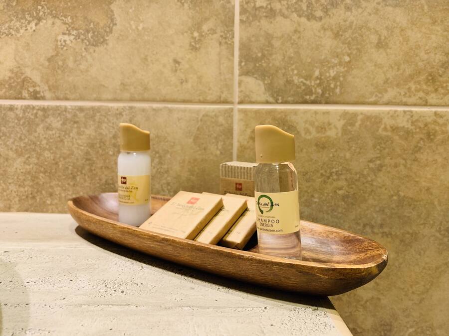 Un plateau en bois avec trois bouteilles et deux savons, posé sur le comptoir d’une salle de bain.