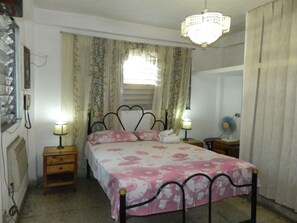 A bedroom with a bed, bedside lamps, a fan, a telephone, and a chandelier. - Casa de Ilsia y Migdonio (Santiago de Cuba)