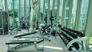 Ein Fitnessstudio mit verschiedenen Trainingsgeräten, darunter Laufbänder, Kraftgeräte und Kurzhanteln.