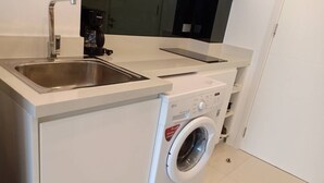 Eine kleine Küche mit integriertem Waschmaschine und einem Spültrog.