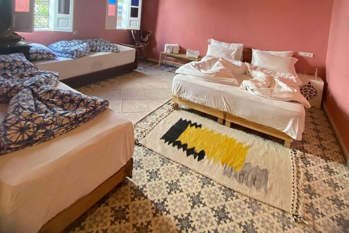 A bedroom with two beds, a patterned rug, and hanging light fixtures.
