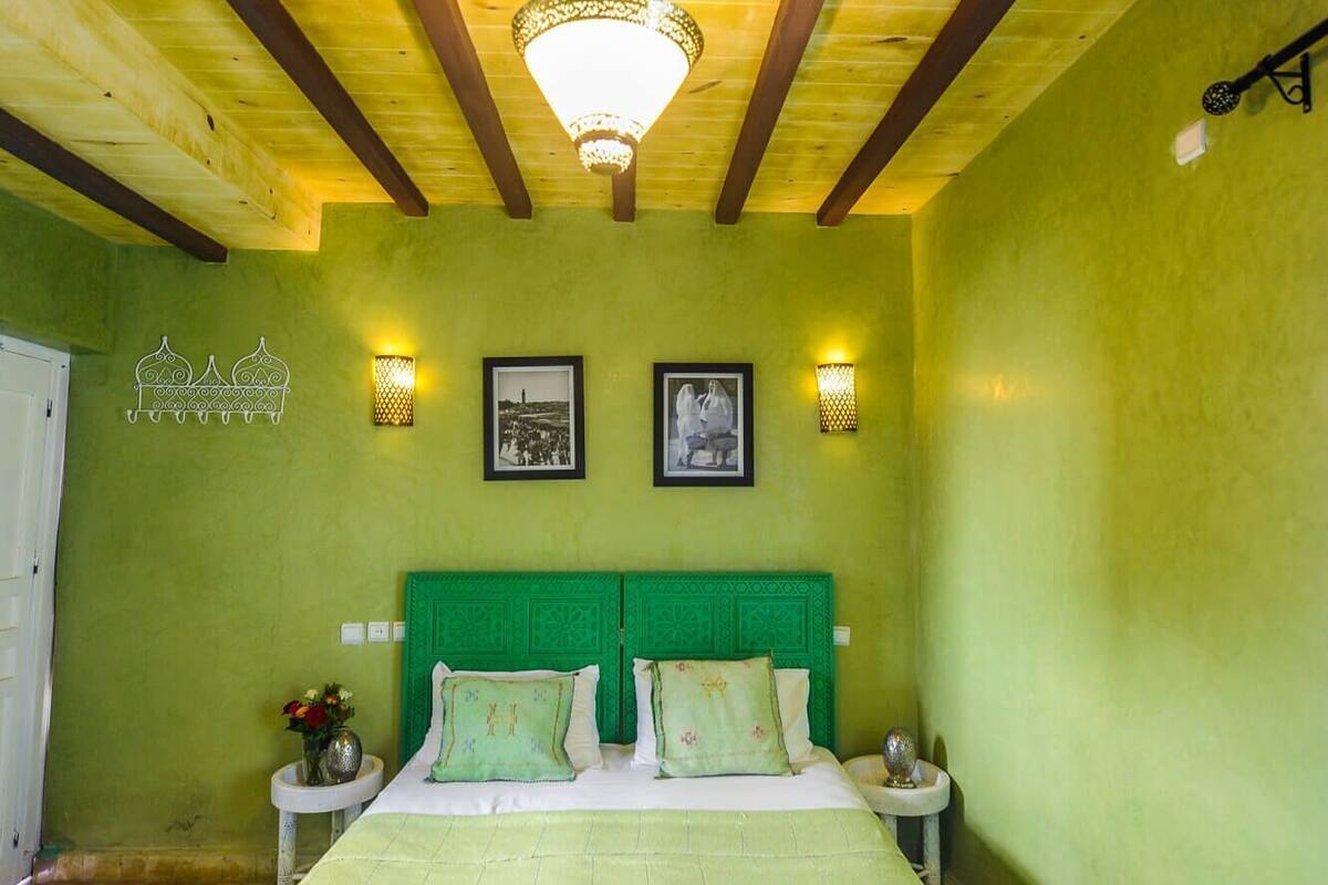 A room with a bed, two bedside tables, a hanging light fixture, and two wall-mounted lights.