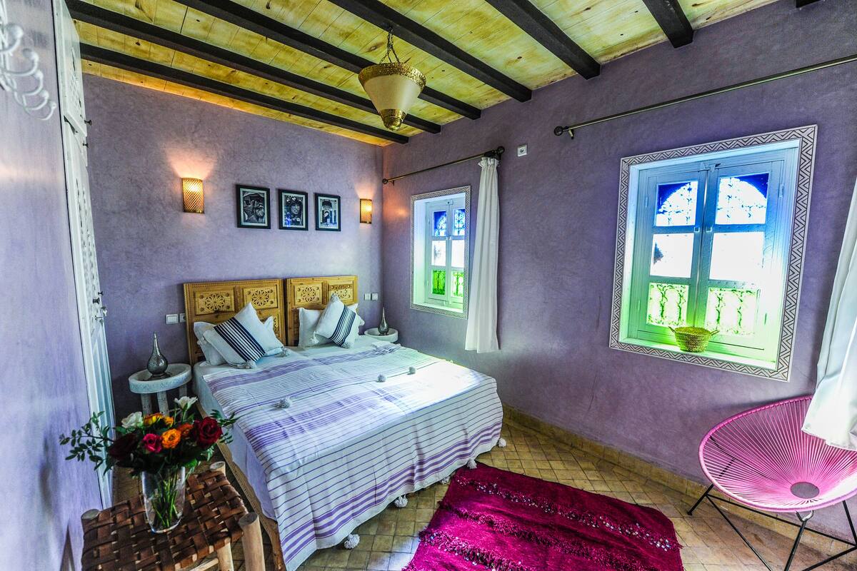 A bedroom with a bed, bedside tables, a chair, and a window with a view.