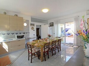 A modern kitchen with a dining area, featuring a large table and chairs, a microwave, and cabinets. - La Rosa by Interhome (Montelupo Fiorentino)