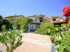 A residential area with a paved courtyard, a house with a balcony, and a red flower in the foreground. - La Rosa by Interhome (Montelupo Fiorentino)