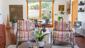 Un salon avec des canapés à motifs, une table basse et un coin repas comprenant des chaises et une table.