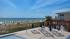 Un complexe hôtelier en bord de mer, doté d’une piscine, de chaises longues et de parasols.
