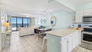 A modern kitchen with a dining area, a large window overlooking the ocean, and a balcony with a view. - Beachfront Seaside 5516, 2/2 Sea South Properties (Orange Beach)