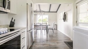 Een moderne keuken met een eethoek, inclusief een ingebouwde magnetron, roestvrijstalen apparatuur en een eettafel met stoelen.