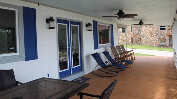 A covered patio with outdoor seating, a stone wall, and a screened porch area. - Sunset Cottage on Lake Wateree with Dock AND Ramp in a COVE (Camden)