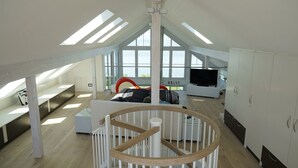 Un'ampia camera loft con lucernari, un'ampia finestra, un letto, una TV e un armadio.