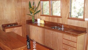 Une cuisine avec des meubles de rangement en bois, un plan de travail, un évier, une fenêtre et un vase rempli de fleurs.