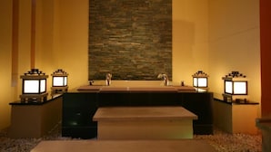 A bathroom with a stone wall, two sinks, and four illuminated lantern-style lights.