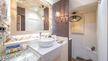 Un baño moderno con un espejo grande, un lavabo blanco y un perchero para toallas.