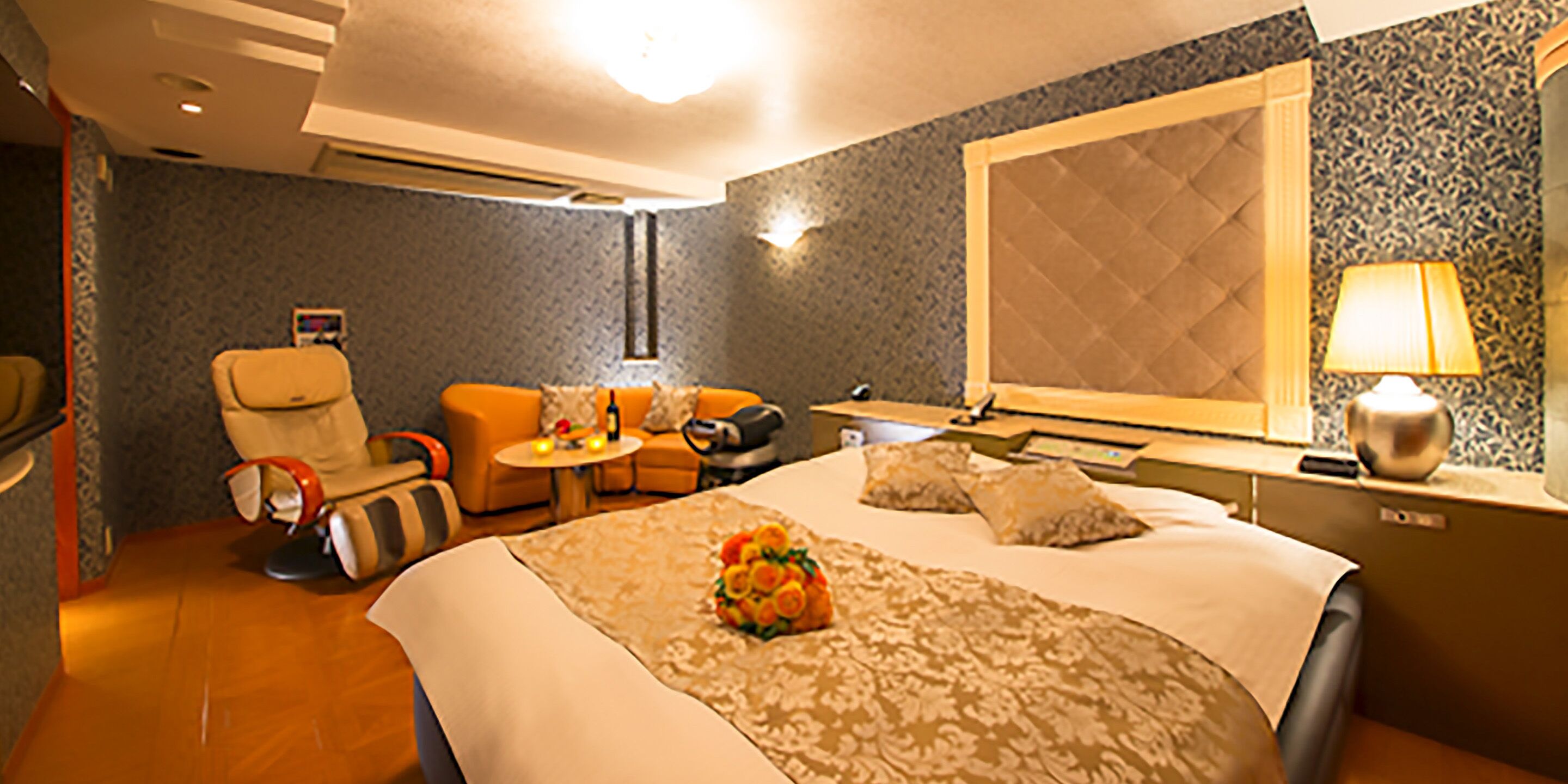 Een hotelkamer met een bed, een bank, een stoel, een klein tafeltje en een lamp.