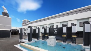 A modern hotel with a swimming pool, a statue, and a sign reading "HOTEL GT ZITIE".