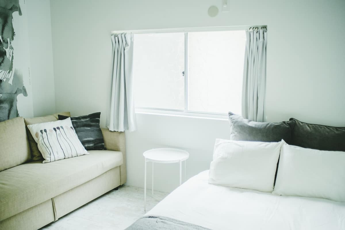 A room with a bed, a sofa, a small table, and a window with curtains.