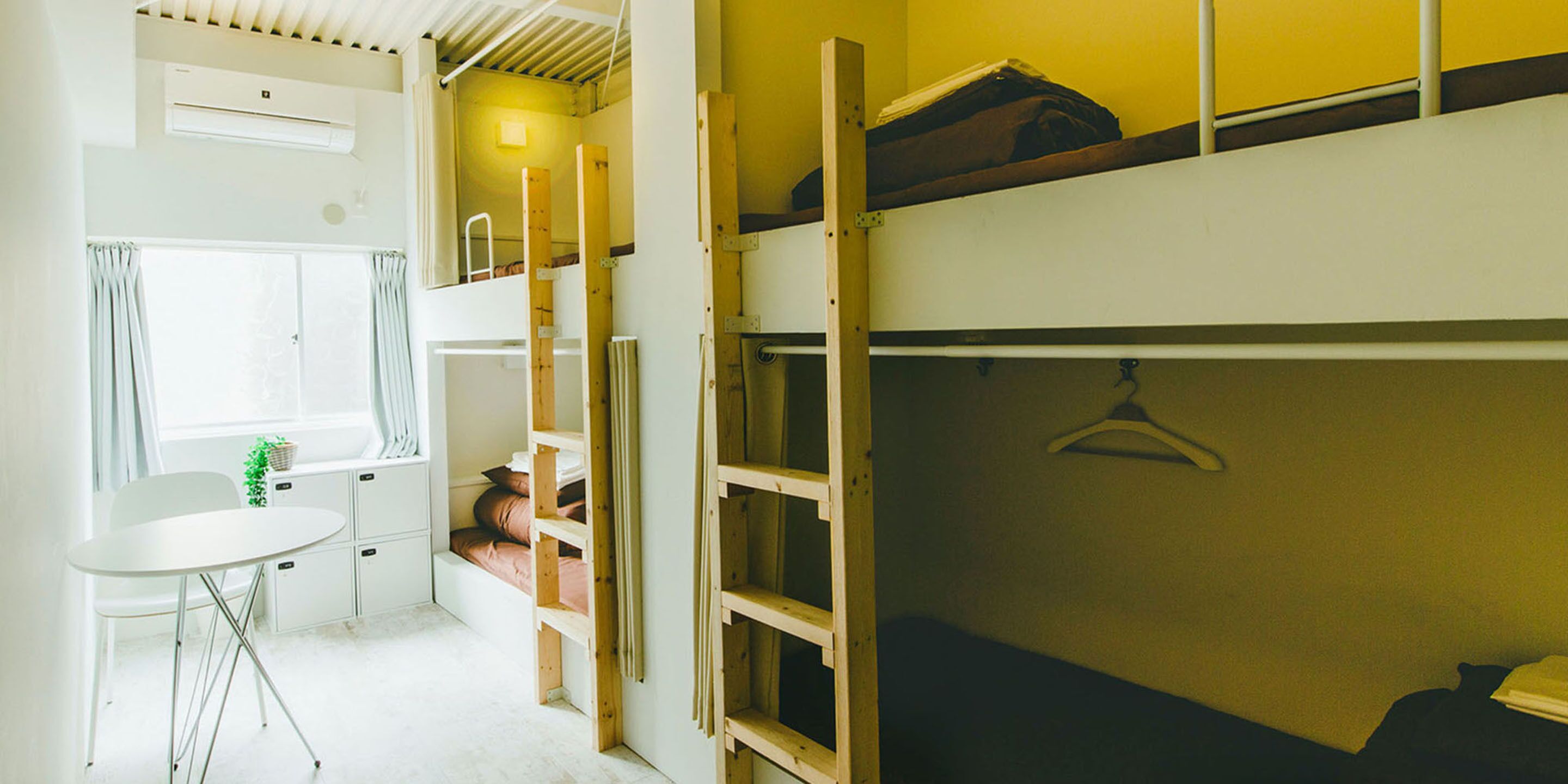 A bunk bed room with a small table and a window.