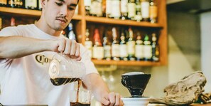 A person pouring a dark liquid into a glass. - HIPPO Hostel & Cafe Bar (Osaka)