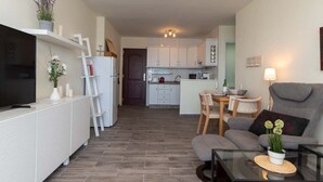 Un salon moderne avec un téléviseur à écran plat, un canapé gris et une table basse.