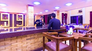 A restaurant with wooden furniture and a counter. - Midpoint Inn Resort (Ghankatta)