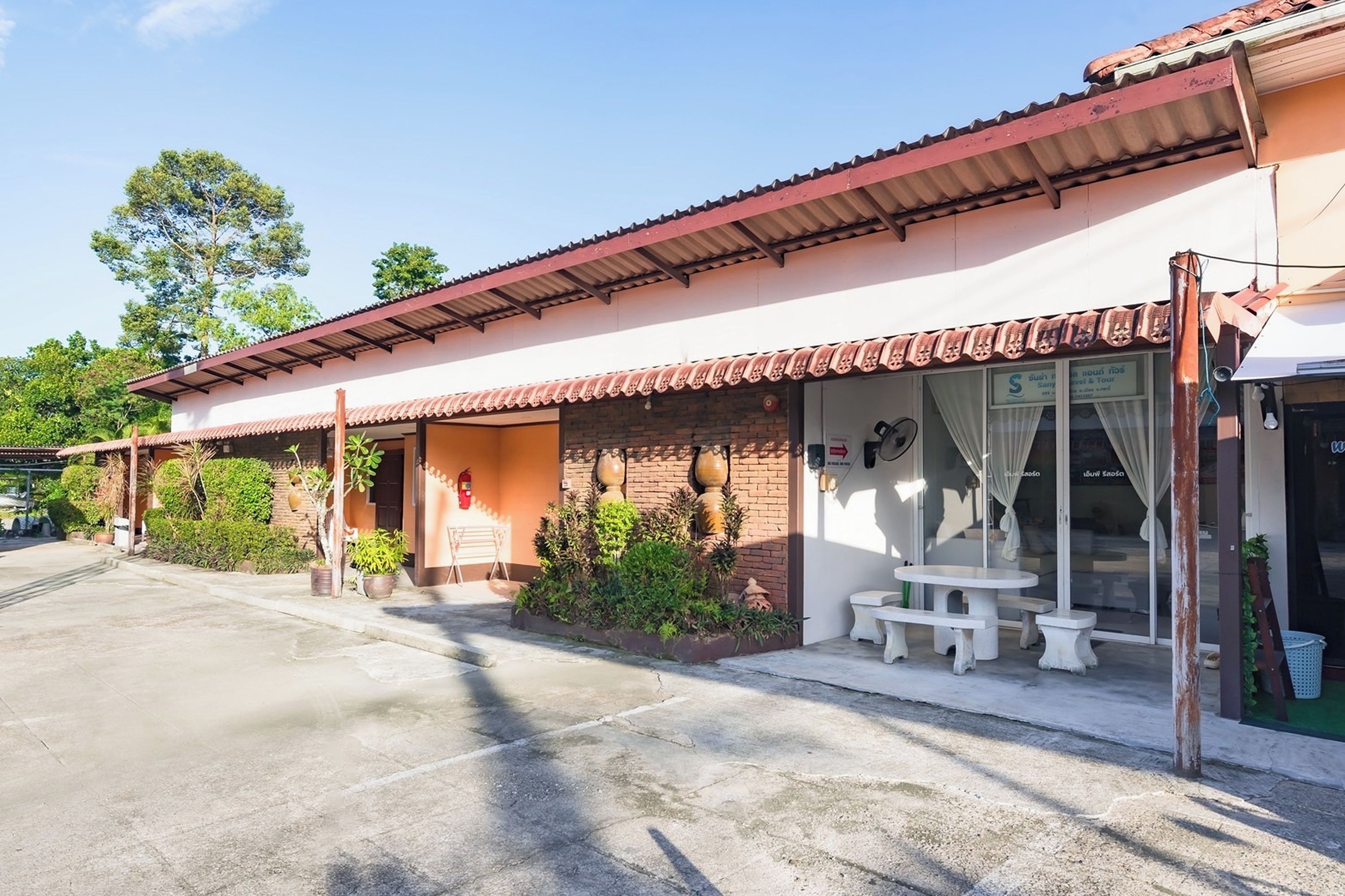 A two-story building with a tiled roof, a covered porch, and a small outdoor seating area.
