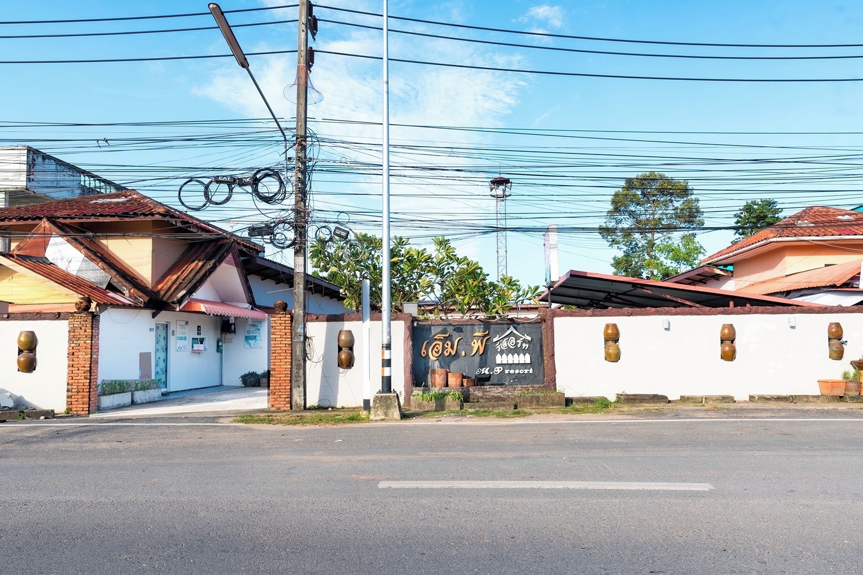Vista da rua com um edifício identificado como 'M. P. Resort' e céu claro.